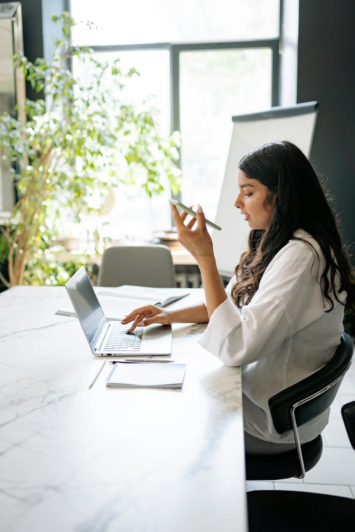 Indian dentist at desk multitasking with laptop and phone — DARA chat in flow